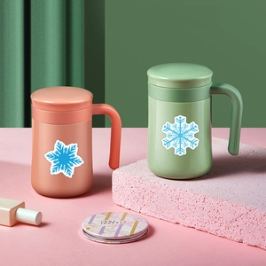 Close-up of pink and green Christmas mugs with snowflake patterns on a pastel display