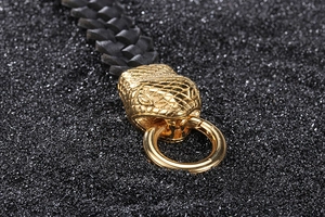 Macro shot of detailed golden twin snake heads on black braided leather bracelet