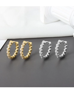 Detailed view of twisted rope hoop earrings in gold and silver finish with zircons