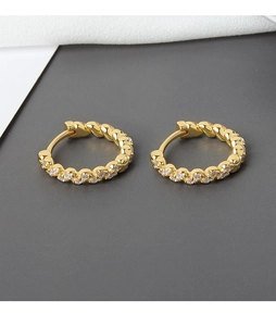 Macro shot of gold-plated hoop earrings featuring twisted texture and white zircon stones