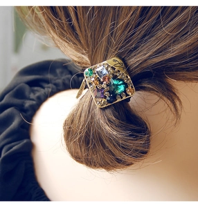 Vue détaillée d'un élastique à cheveux vintage doré avec strass colorés et pierre verte