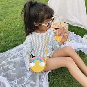 Girl's yellow round crossbody bag with rainbow sequin design on a picnic grass background