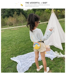 Detail showing a girl wearing a yellow round rainbow crossbody bag in an outdoor setting