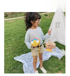 Little girl wearing a yellow round crossbody bag with rainbow sequins in outdoor garden