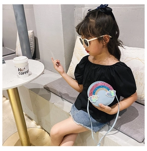 Girl wearing blue rainbow sequin crossbody bag in a bright cafe setting