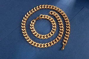 Detailed view of golden Cuban link chain set with necklace and bracelet on blue background
