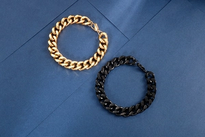 Detail view of bold Cuban link necklaces in gold and matte black with lobster clasps