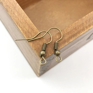 Macro shot of antique bronze earring hooks with coils and beads on a wooden edge
