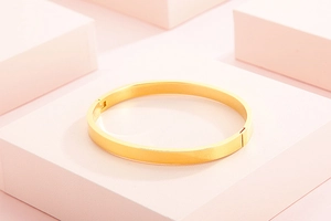 Gros plan d'un bracelet jonc en acier doré poli avec un fermoir à charnière sécurisé