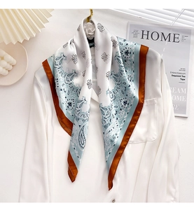 Close-up of elegant paisley pattern on silk scarf with blue and brown border detail