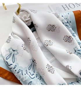 Close-up of paisley silk scarf with orange contrast hem and smooth satin texture