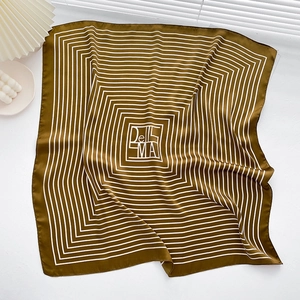 Detailed view of striped silk scarf with brown and white geometric patterns and DELEMA text