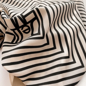Macro shot of striped silk-like scarf featuring geometric maze patterns and letter e detail