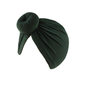 Detail des weichen dunkelgrünen Strickstoffs und handgemachten Knotens der Baby-Turbanmütze