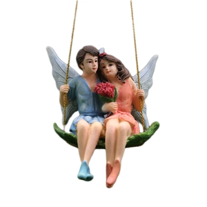 Miniature resin couple fairy figurines sitting on a leaf swing with gold hanging cord