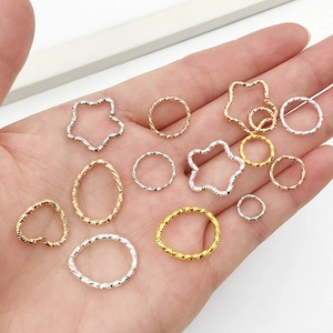 Close-up of assorted gold and silver geometric DIY jewelry charms on a hand