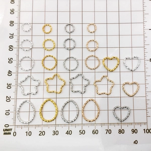Assorted geometric alloy charms in gold and silver colors on a metric measuring mat