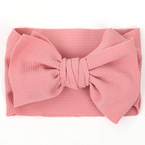 Close-up of wide dusty rose baby headband with textured bubble fabric and large bow