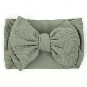 Detailed close-up of sage green baby headband with large bow and ribbed fabric texture