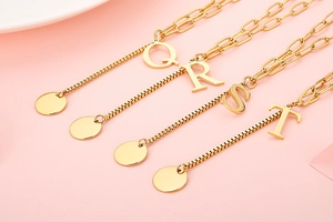 Detailed shot of golden alphabet pendants Q R S T on unique mixed chain necklaces