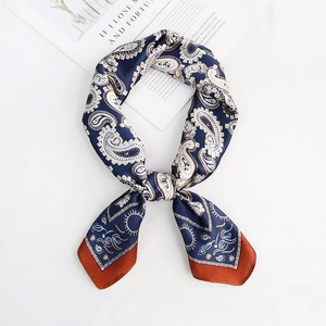 Flat lay of navy blue paisley silk scarf with orange border and elegant knotted styling