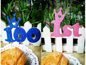 Close-up of glittery number 100 and 1st cake toppers with crown and heart cutout details