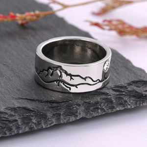 Macro-opname van ring met bergmotief en zirkoon op stenen plaat met droogbloemen