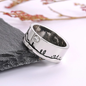 Detail van zilveren ring met berglandschap lijntekening en glanzende zirkoonsteen