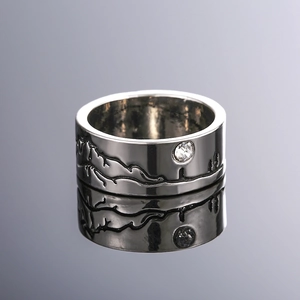 Detailopname van de zilveren ring met berggravure en kleine gezette zirkonia