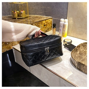 Detail of black quilted PU leather cosmetic bag with dual silver zippers and handle
