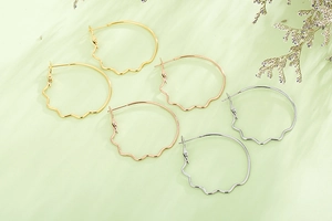 Chic wavy edge large hoop earrings in gold, rose gold and silver finishes on green background