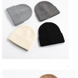 Flat lay of ribbed knit cuffed beanies in grey, cream, and black for winter warmth