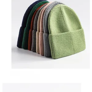 Detail view of multi-color ribbed knit beanies in navy, green and grey colors