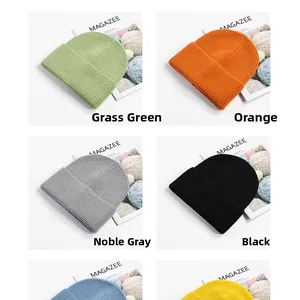 Detail of knitted beanies in green, orange, grey and black with a warm ribbed texture
