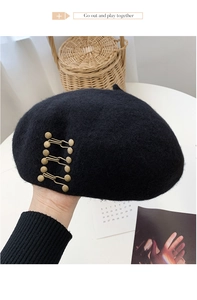 Detail of black wool beret with three antique bronze metal buckles on a soft background
