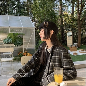 Classic black wool beret with metal pin accent paired with a retro plaid autumn outfit
