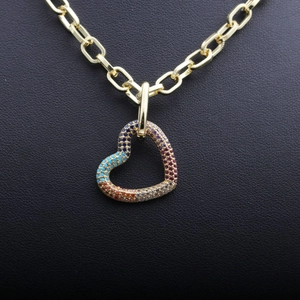 Hip Hop gold necklace with colorful zircon heart pendant on textured black background