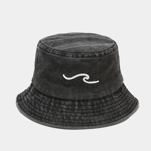 Macro detail of wave embroidery and metal eyelets on washed denim bucket hat