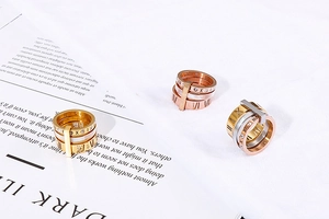 Detail of tricolor stainless steel layered rings with Roman numerals and zircons