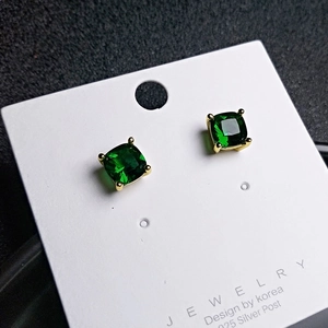 Macro detail of cushion-cut green gemstone studs with 925 silver posts on a display card