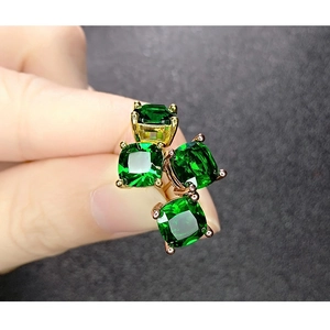 Detailed close-up of four-prong square cut green crystals set in elegant metal studs