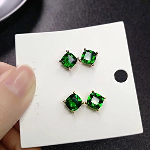 Detail of square-cut green emerald earrings in rose gold and gold four-prong settings