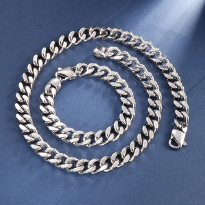 Vue détaillée d'un ensemble collier et bracelet gourmette argenté sur fond bleu texturé