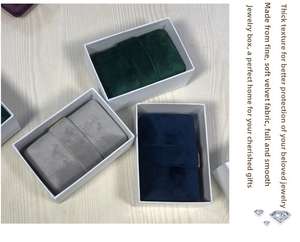 Detailed view of velvet jewelry boxes in dark green, gray, and navy with gold buckles