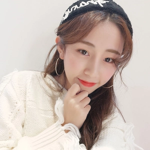 Close-up of large gold hoop earrings paired with a black embroidered headband and white sweater