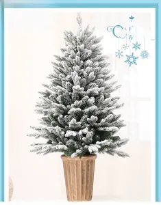 Close-up of mini snow-covered PE Christmas tree in vintage brown pot for desk decor