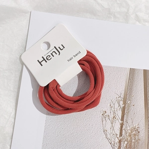 Detailed shot of brick red elastic fabric hair tie on a minimalist white card tag