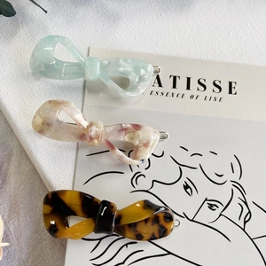 Classic acetate bow hair clips in green, marble beige, and tortoiseshell colors