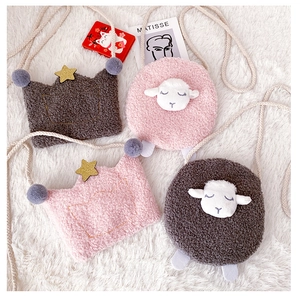 Flat lay of plush cartoon kids crossbody bags in crown and sheep designs on white fur