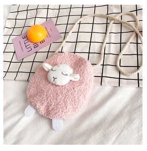 Flat lay of pink plush lamb crossbody bag with embroidered details on checkered cloth